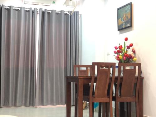 岘港Căn hộ nghỉ dưỡng Mường Thanh apartment的餐桌,带两把椅子和花瓶