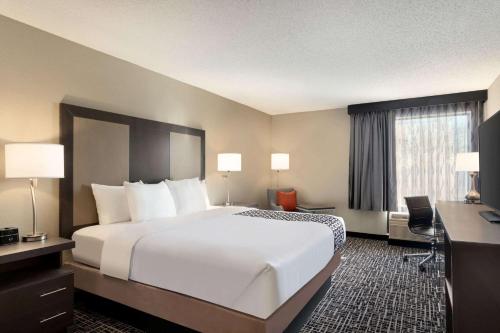 圣路易斯La Quinta Inn & Suites by Wyndham St Louis Route 66的酒店客房设有一张大床和一张书桌。