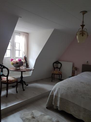 EeTERP WONING bij Schiermonnikoog "Op de Terp" Noordoost Friesland的一间卧室配有一张床和一张鲜花桌子