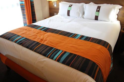 巴黎巴黎蒙马特智选假日酒店的一张大床,上面有橙色毯子
