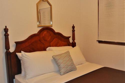 格兰福克Arhaus 2的一张带木制床头板和白色枕头的床