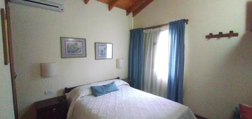 贝尔格拉诺将军镇Lo de la Omi的一间卧室配有床和蓝色窗帘的窗户
