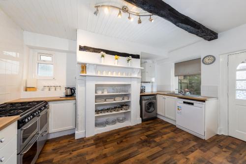 雷文格拉斯Muncaster Cottages的一间大厨房,配有白色的橱柜和炉灶