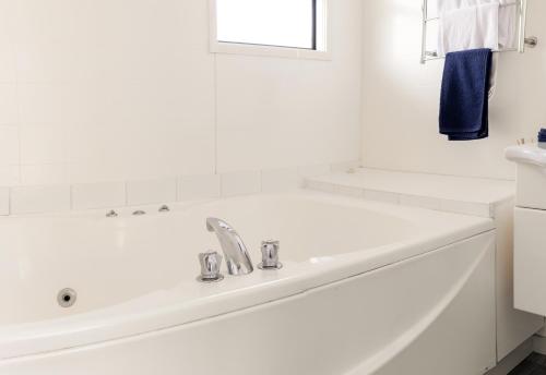 Snells Beach斯涅海滩汽车旅馆的白色的浴室设有浴缸和水槽。