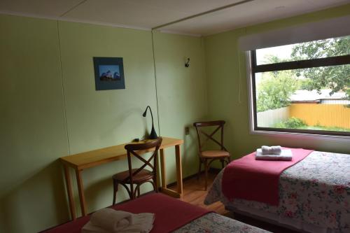 纳塔列斯港Asói Hostal的一间卧室配有一张床、一张书桌和一个窗户。