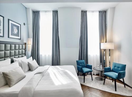 维也纳施泰根博阁庄园酒店的一间卧室配有一张床和两张蓝色椅子