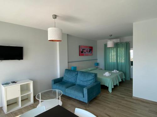 莫哈卡尔Mda Playa del Cantal的客厅配有蓝色的沙发和床。
