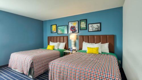 康科德Uptown Suites Extended Stay Charlotte NC - Concord的两张床铺,房间拥有蓝色的墙壁和黄色的枕头