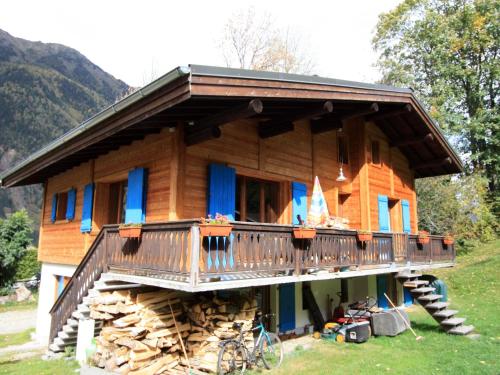 夏蒙尼-勃朗峰B&B Chalet Les Frenes的小木屋,在一堆木头上设有阳台