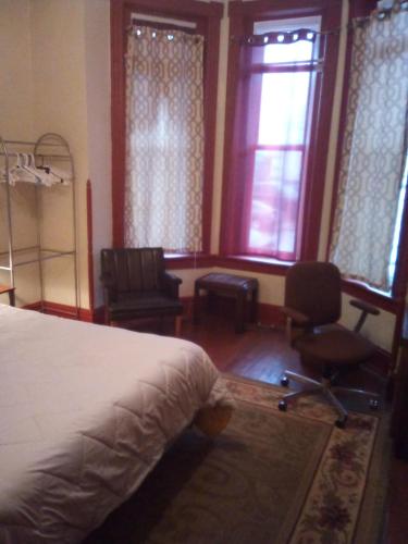 里士满Orange Wildflowers的一间卧室配有一张床、两把椅子和窗户