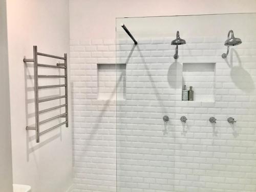 拜伦湾Arcadia House的一间带淋浴的浴室,配有白色砖墙