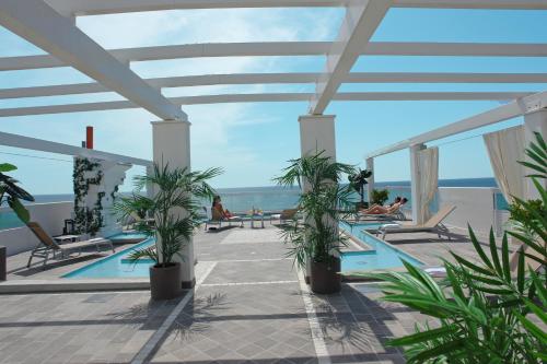利多迪耶索罗奥里宗酒店的一座棕榈树游泳池,人们坐在椅子上