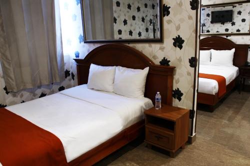 蒙特雷El Regio的一间卧室配有两张床和一张带一瓶水的桌子。