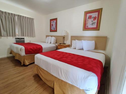 劳德代尔堡皇冠旅馆的酒店客房,配有两张带红色床单的床