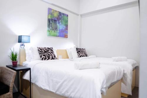 土格加劳Radlett Residences Hotel - Tuguegarao的一间卧室配有两张带白色床单的床
