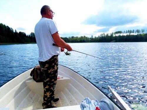VäjaLila Stuga的站在渔船上,持钓 ⁇ 的人