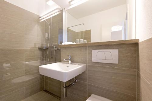 施泰克博恩费尔德巴赫喜百樂酒店的一间带水槽和玻璃淋浴的浴室