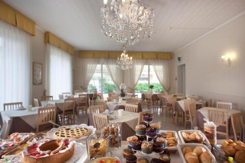 里米尼Hotel Villa Perazzini的用餐室配有带糕点的桌子