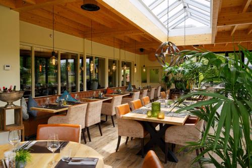 博尔讷亚克洛斯特酒店的餐厅设有木桌和椅子,种有植物