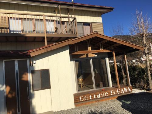 富士河口湖コテージトガワ＜Cottage TOGAWA＞的一座带大窗户和阳台的建筑