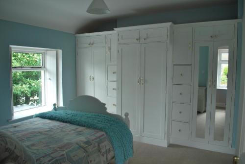 班多伦5 Ellesmere Avenue的卧室配有白色橱柜、床和窗户。