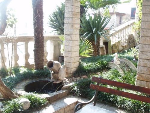 里耶卡Apartment Mira的花园中的喷泉,花园内种有长凳和棕榈树