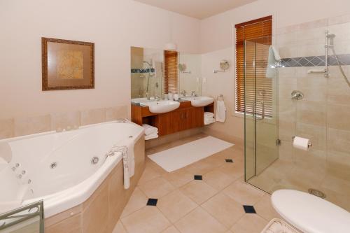 北帕默斯顿Hiwinui Country Estate的带浴缸、两个盥洗盆和淋浴的浴室。