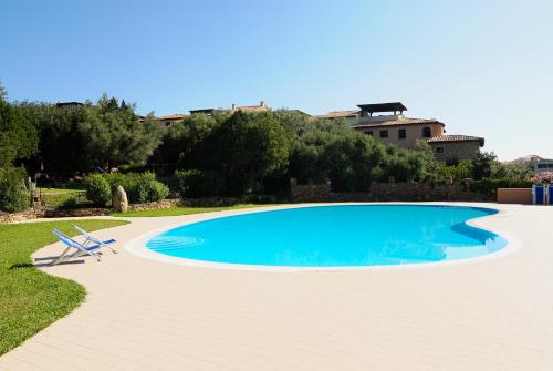 罗通多港Residence Portorotondo Tre的一个带椅子和房子的蓝色游泳池