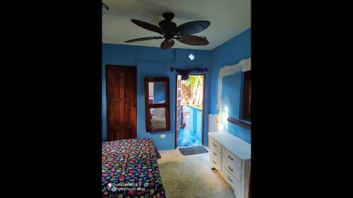 喀巴里特Room in Lodge - Method Living Tropical Edition的一间卧室设有蓝色的墙壁和吊扇。