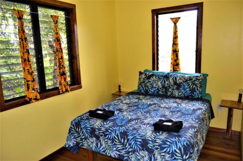 圣伊格纳西奥Iguana Roost Tourism Gold Standard Fully Equipped two Bedroom Cabin的一间卧室配有一张带蓝色床单的床和两个窗户。