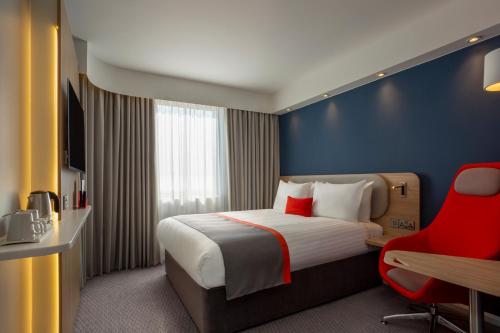 巴罗弗内斯Holiday Inn Express - Barrow-in-Furness & South Lakes, an IHG Hotel的酒店客房,配有一张床和一张红色椅子
