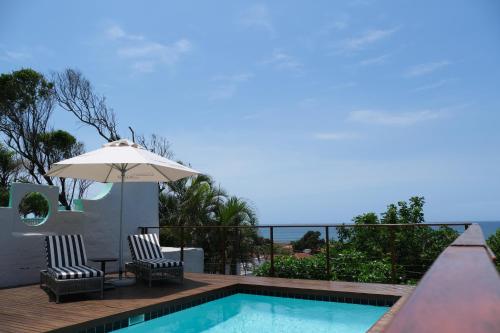 德班Ocean Vista Boutique Guest House的一个带两把椅子和遮阳伞的游泳池