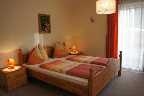 弗拉塔赫Appartementhaus Alpina的一间卧室配有一张木床,桌子上配有两盏灯