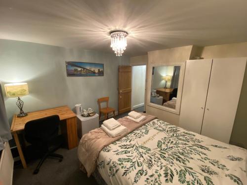 科尔切斯特Prince Cottage的一间卧室配有一张床、一张书桌和一面镜子
