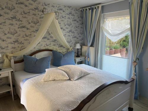 博尔滕哈根Gästehaus Schmidt的一间卧室配有一张带天蓬和窗户的床