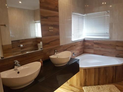 比勒陀利亚Cornerstone Guest Lodge的浴室配有浴缸、两个盥洗盆、浴缸和浴缸。
