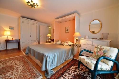 Genolier乐利尔家庭旅馆的一间卧室配有一张床、一把椅子和镜子