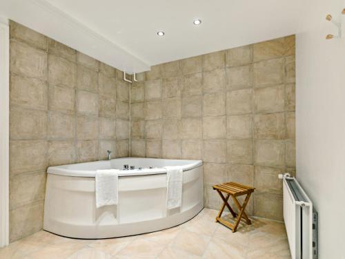 Løgstør勒格斯特公园酒店的浴室设有白色浴缸,铺着瓷砖。