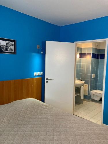 圣奈L'ETAPE DE SANTENAY的一间蓝色的卧室,配有一张床和一间浴室