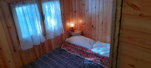 MarsiaEUROPING VILLAGE MARSIA Abruzzo的木制客房的一张小床,设有窗户