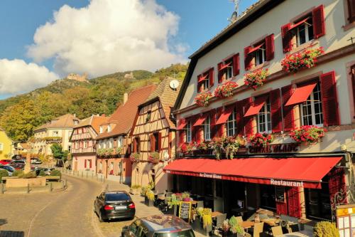 希伯维列Hotel SPA Restaurant Au Cheval Blanc的城镇中拥有建筑物和汽车的街道