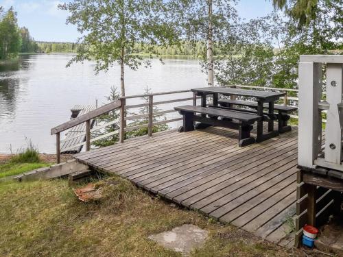 Juhanala卡瓦洛凯皮洛提度假屋的湖畔木甲板上的野餐桌和长凳