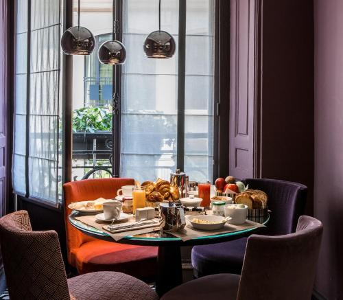 巴黎芒萨尔法兰西精神酒店的一张桌子,上面有早餐食品,放在一个窗口的房间