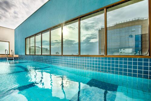 圣保罗INNSiDE by Meliá São Paulo Iguatemi的一个带蓝色瓷砖和窗户的大型游泳池