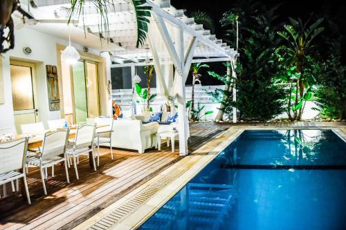 普罗塔拉斯Riverland beach villa的庭院设有游泳池、桌子和椅子。