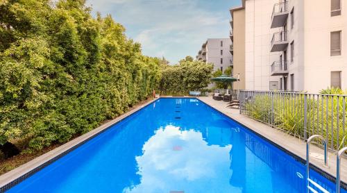 悉尼Oaks Sydney North Ryde Suites的一座拥有树木和建筑的蓝色游泳池