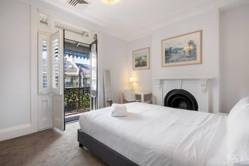 悉尼BRID243FL - The Terrace on Bridge的一间白色卧室,配有一张床和一个壁炉