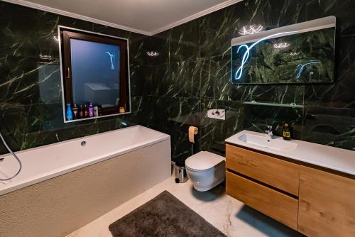 阿拉德MOKY REZIDENT 2的带浴缸和水槽的浴室以及电视。