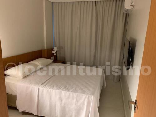 萨利诺波利斯Apartamento em Resort - Exclusive的卧室配有白色的床和电视。