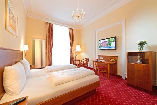 巴登-巴登施韦策霍夫高级酒店的酒店客房配有一张床铺和一张桌子。